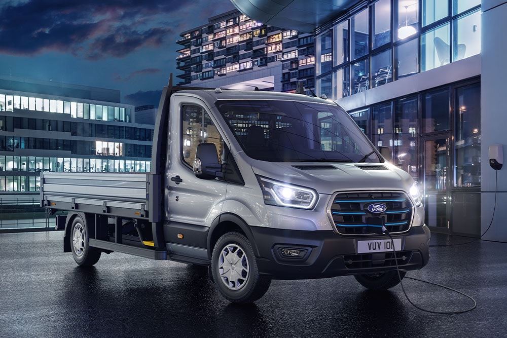Ford E-Transit Chassis Cab argento parcheggiato di notte di fronte a un edificio moderno.