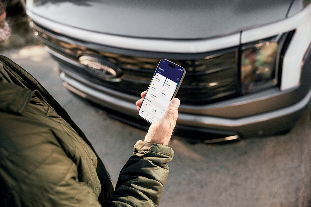 Un uomo che controlla il suo smartphone davanti a un Ford Ranger.