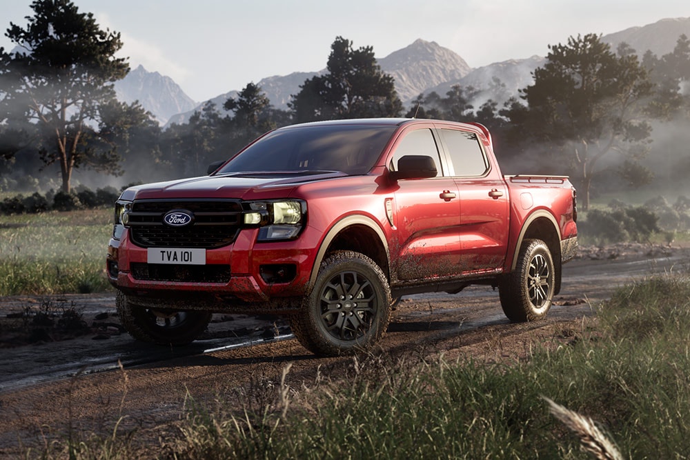 Un Ford Ranger Raptor rosso che percorre una strada sterrata attraverso un paesaggio panoramico.