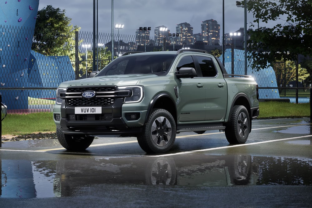 Un Ford Ranger PHEV grigio parcheggiato di fronte a un paesaggio urbano al crepuscolo.