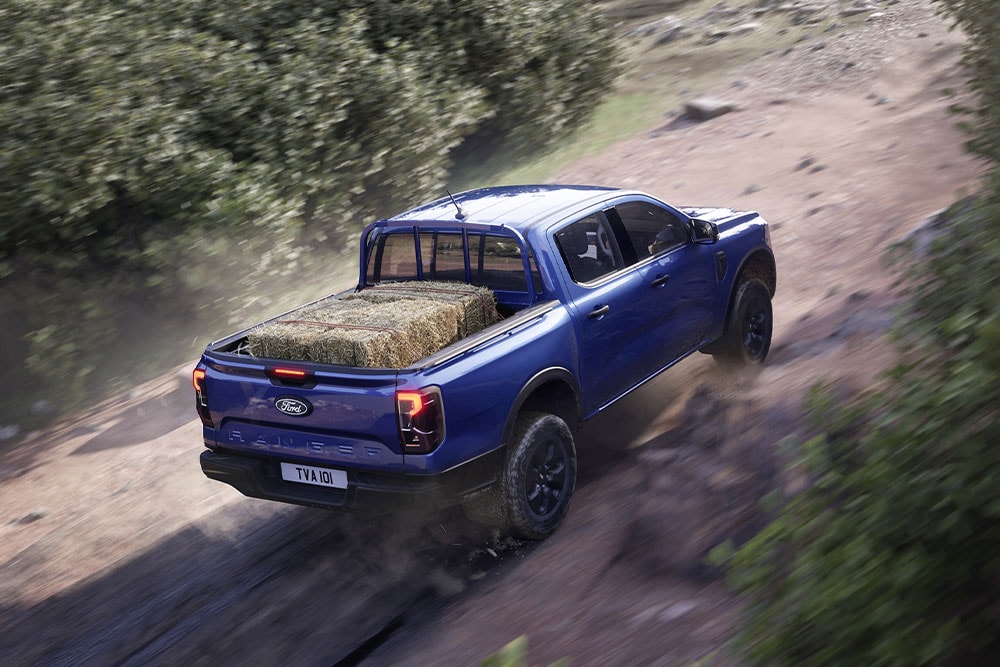 Vista posteriore superiore di un Ford Ranger blu che percorre una strada sterrata.