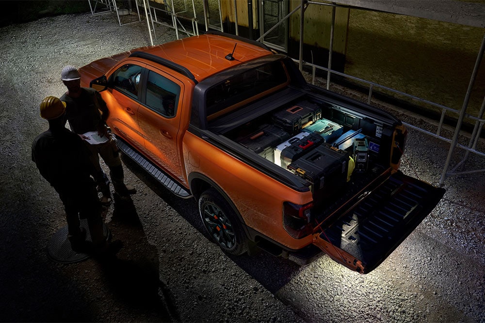 Vista dall’alto del Ford Ranger Wildtrak arancione di notte con illuminazione della zona esterna.
