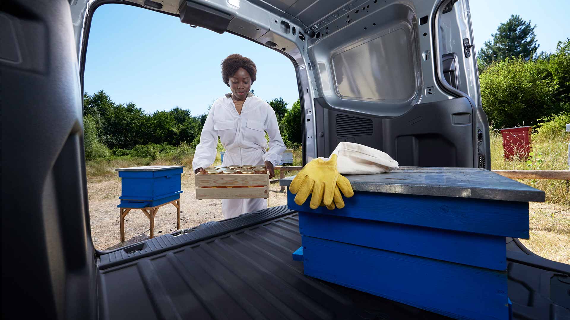 Un apicoltore carica del miele su un Ford Transit Courier.
