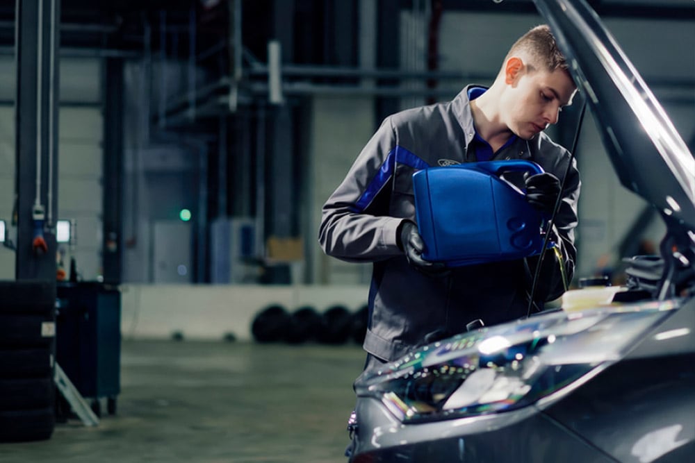 Vista laterale di un tecnico autorizzato Ford mentre effettua riparazioni su un veicolo in un'autofficina.