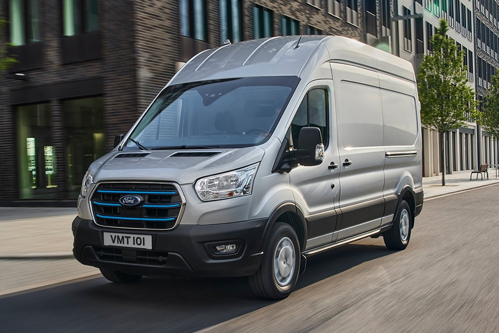 Un Ford Transit color argento che attraversa un paesaggio urbano.