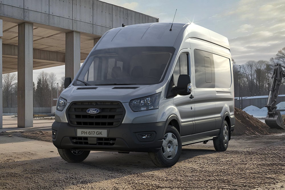 Ford Pro Transit color argento parcheggiato in un cantiere, con operai edili sullo sfondo.