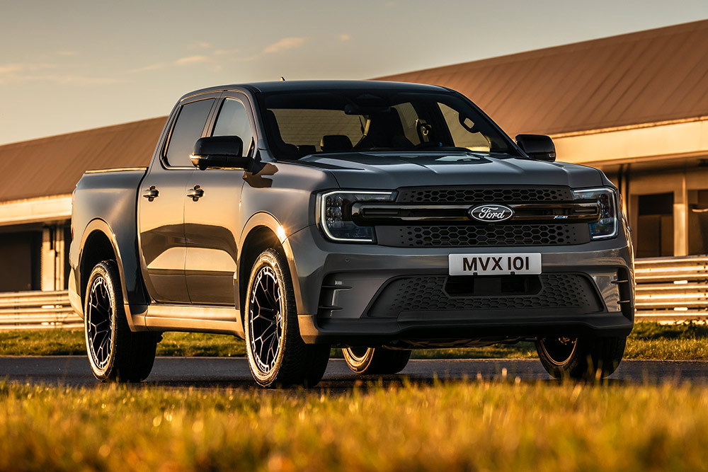 Ford Pro Ranger Plug-in Hybrid color argento parcheggiato di fronte a un edificio industriale.
