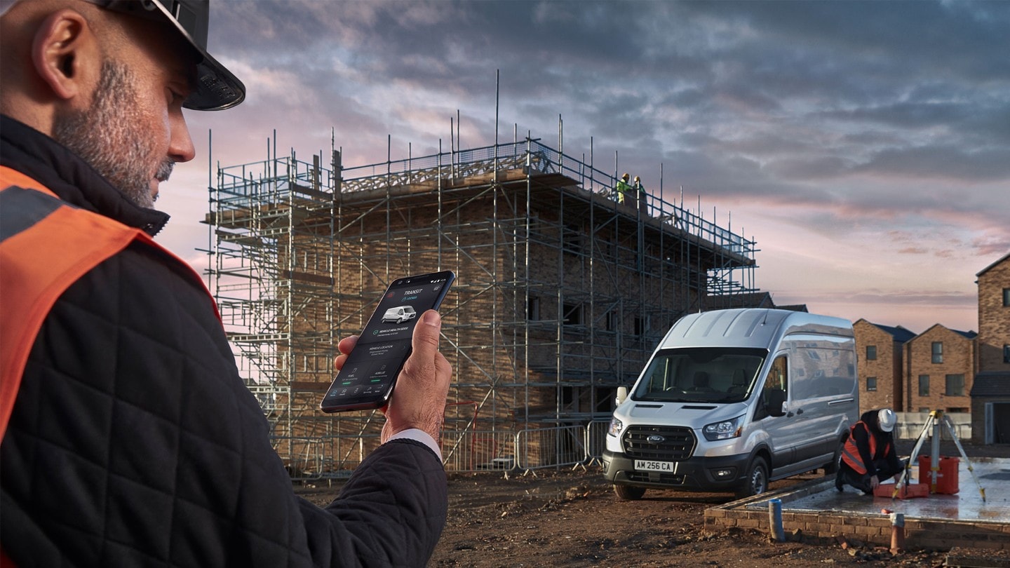 Operaio in un cantiere con telefono cellulare in mano