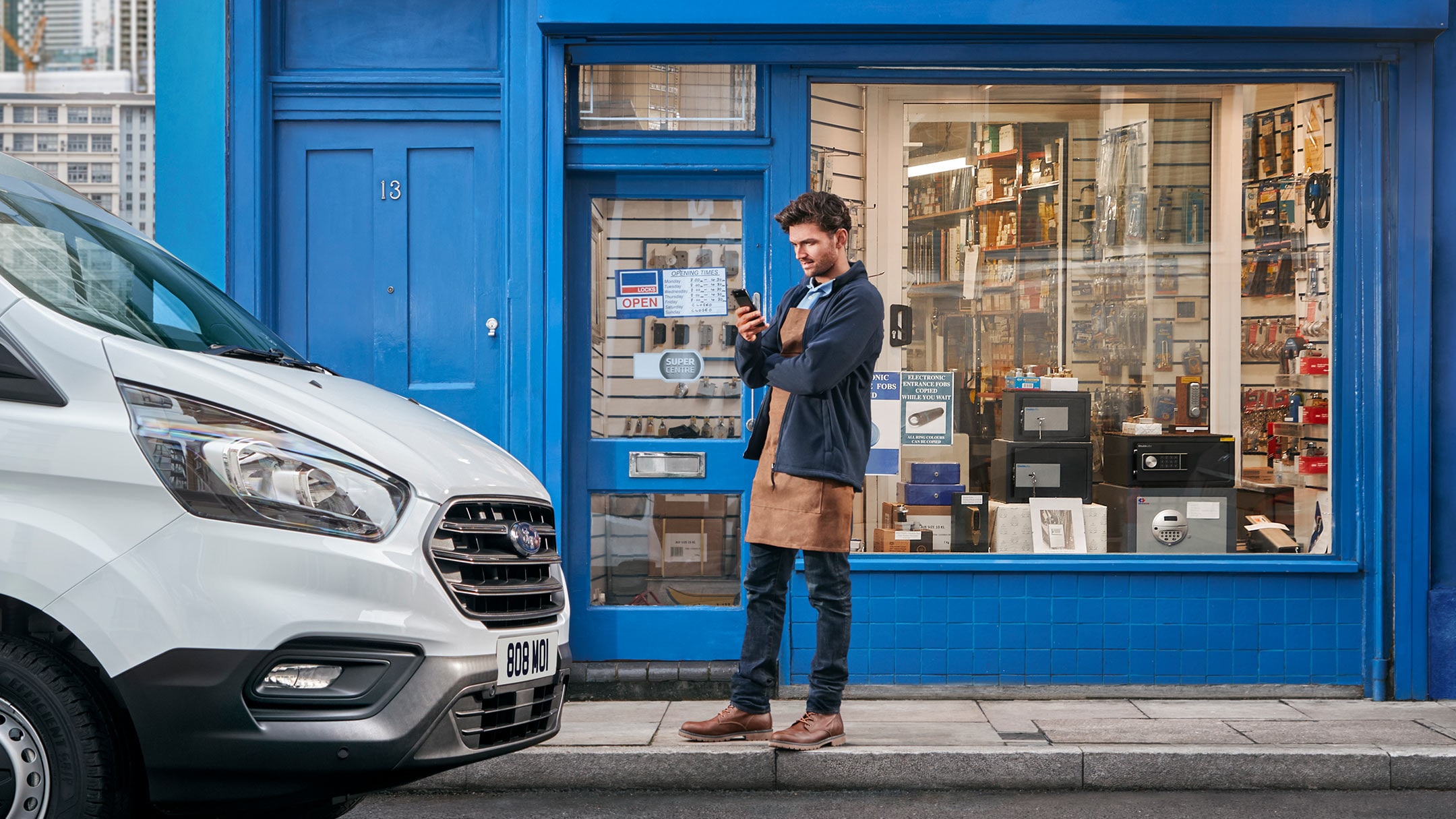 Uomo davanti a un negozio accanto a un veicolo aziendale con il telefono cellulare in mano