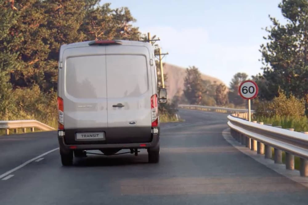 Ford Transit Van in marcia su strada con cartello, vista posteriore