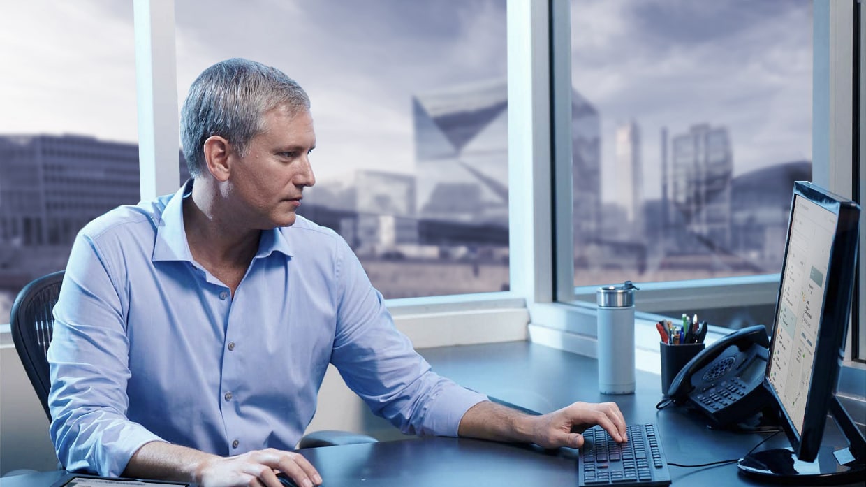 Un uomo seduto alla scrivania guarda lo schermo del computer